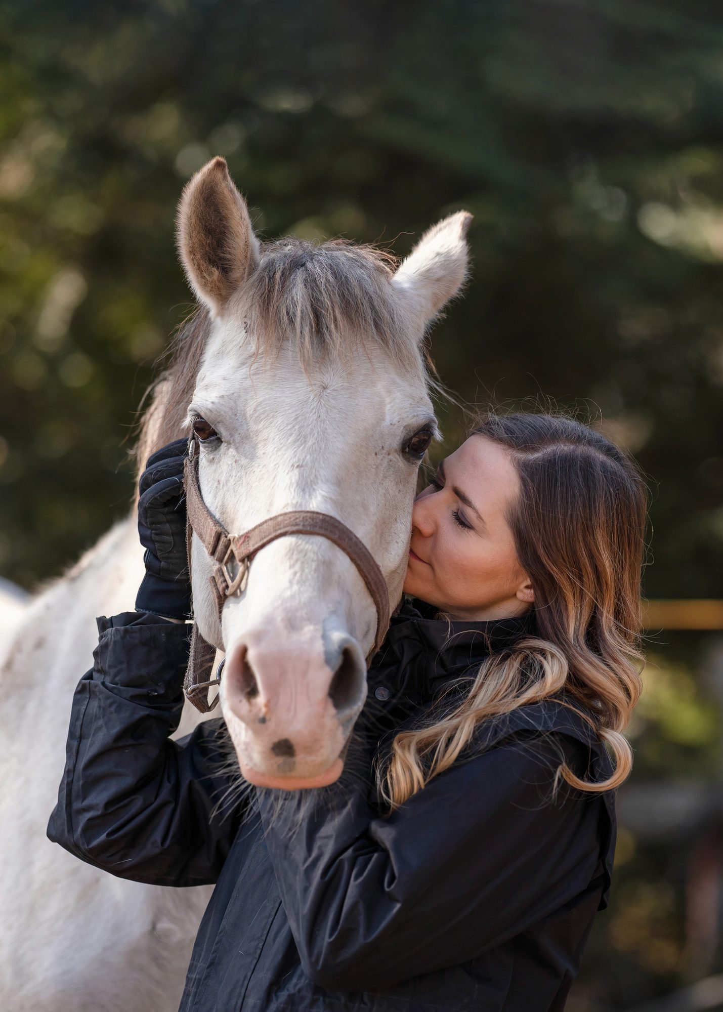 An owner holding her grey horse close